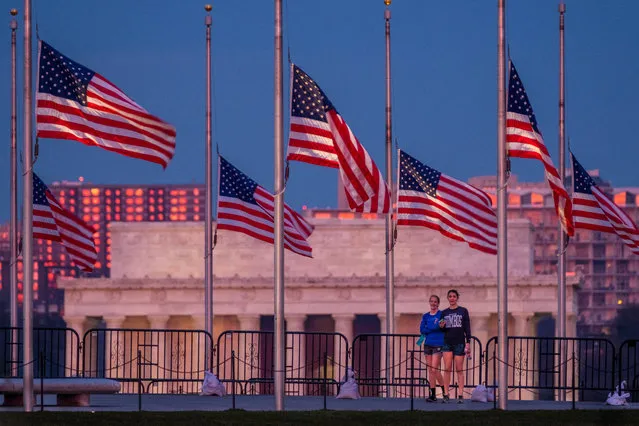 Visitors to the Washington Monument walk under flags flying at half-staff early Wednesday, March 23, 2016, honoring the victims of the Brussels attacks, in Washington. In the background is the Lincoln Memorial. (Photo by J. David Ake/AP Photo)
