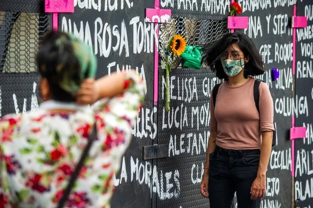 A woman is seen in front of a metal fence with the names of victims of femicide surrounding the National Palace ahead of the International Women's Day, in Mexico City on March 7, 2021. (Photo by Claudio Cruz/AFP Photo)
