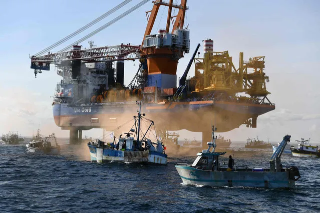 Fishing boats surround the drilling platform ship “Aeolus” in the Bay of Saint-Brieuc, western France on May 7, 2021, to protest against the planned construction of 62 wind turbines offshore in the bay. (Photo by Fred Tanneau/AFP Photo)