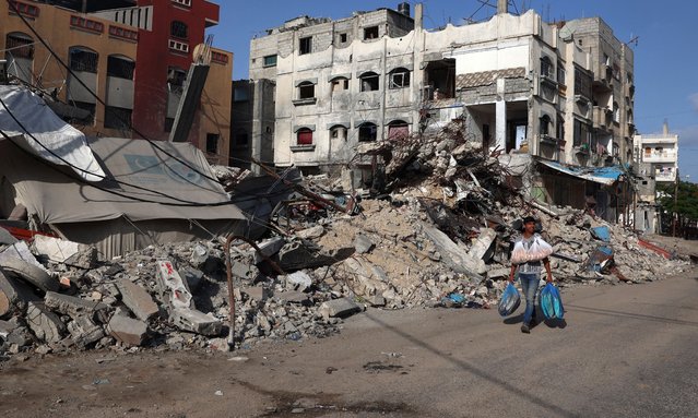 A Palestinian man walks past a destroyed building in Rafah in the southern Gaza Strip on May 26, 2024, amid the ongoing conflict between Israel and the Hamas militant group continues. (Photo by Eyad Baba/AFP Photo) 