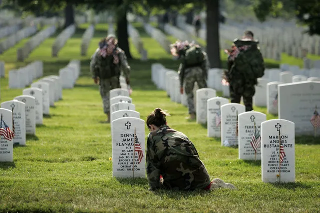 Kristin Kenney of Edison, N.J. sits at the grave of her boyfriend, Army Sgt. Dennis Flanagan, while Members of the 289th Military Police Honor Guard plant flags at grave sites at Arlington National Cemetery  in Arlington, Va. Thursday, May 25, 2006. Flanagan died in Iraq on January 21, 2006. (Photo by Gerald Herbert/AP Photo)