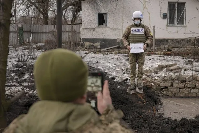 Members of the Joint Centre for Control and Coordination on ceasefire of the demarcation line, or JCCC, take forensic photos of a crater and damage to a house from artillery shell that landed in Vrubivka, one of the at least eight that hit the village today, according to local officials, in the Luhansk region, eastern Ukraine, Thursday, February 17, 2022. U.S. President Joe Biden warned that Russia could still invade Ukraine within days and Russia expelled the No. 2 diplomat at the U.S. Embassy in Moscow, as tensions flared anew in the worst East-West standoff in decades. (Photo by Vadim Ghirda/AP Photo)
