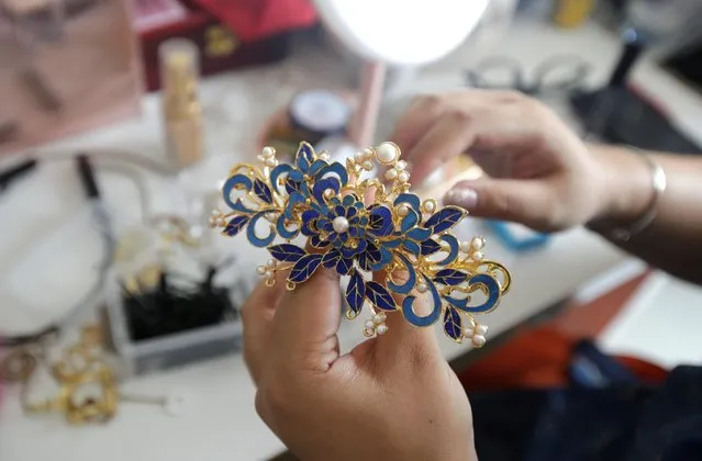 Li Doudou holds a hair ornament as she gets ready to attend a performance of the “guqin” traditional musical instrument, an ancient seven-stringed zither, at her rental home in Hebei province, China on  August 18, 2019. Li is a devotee of the Hanfu movement, which has spanned a decade and in the last year has seen a spike in followers, partly thanks to social media. Li donned her first gown in March and has lost count of the Hanfu outfits in her wardrobe, she says. (Photo by Jason Lee/Reuters)