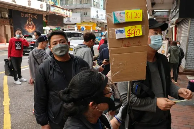 Customers wearing face masks queue up to purchase COVID-19 antigen test kits at a market in Hong Kong, Monday, February 28, 2022. (Photo by Vincent Yu/AP Photo)