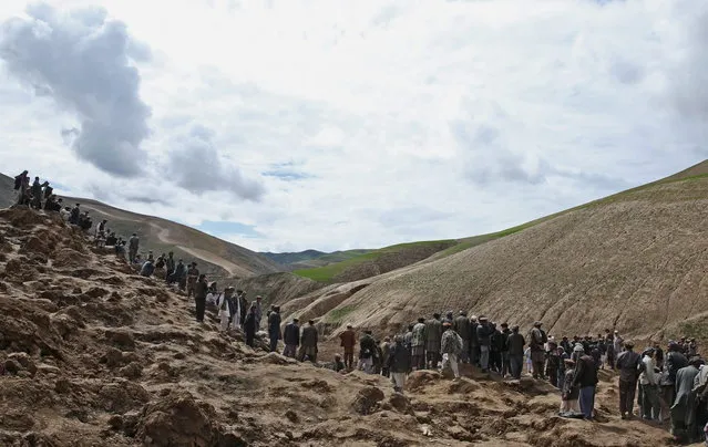 Survivors walk and search for their relatives' bodies at the site of Friday's landslide that buried Abi Barik village in Badakhshan province, northeastern Afghanistan, Monday, May 5, 2014. The landslide was likely triggered by heavy rains that have fallen across northern Afghanistan in recent weeks. It broke off such a massive chunk of earth, burying hundreds of homes, that officials have said it will be impossible to bring up all the bodies. Still, many villagers have continued digging on their own. (Photo by Massoud Hossaini/AP Photo)