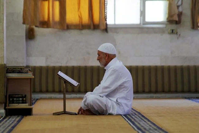 A Muslim man reads the Koran as he prays inside a mosque during the last Friday prayer of the holy month of Ramadan in Idlib city, Syria July 10, 2015. (Photo by Ammar Abdullah/Reuters)