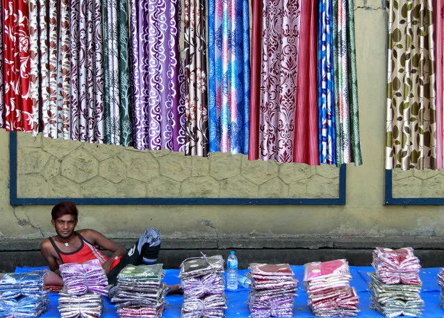 A vendor selling curtains waits for customers on a footpath along a road in Kochi, April 13, 2017. (Photo by Sivaram V/Reuters)