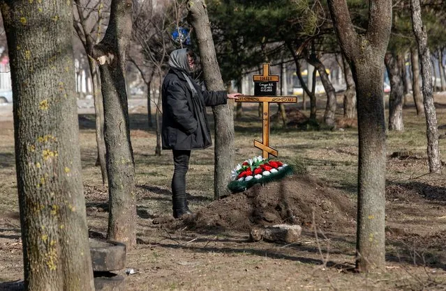 A woman stands next to a grave of her mother killed by shelling during Ukraine-Russia conflict, in the besieged southern port of Mariupol, Ukraine on March 23, 2022. (Photo by Alexander Ermochenko/Reuters)