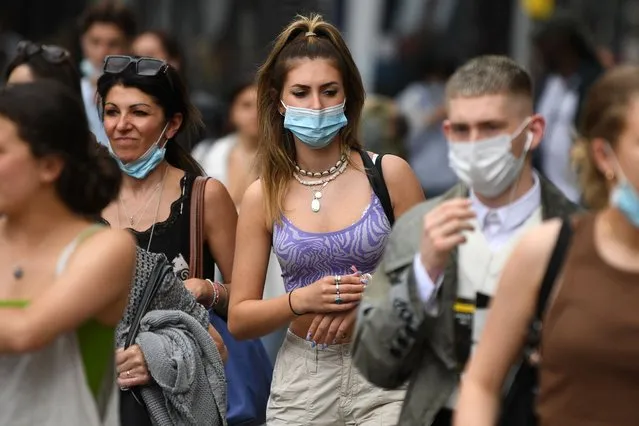 Shoppers wearing protective face coverings to combat the spread of the coronavirus, walk along Oxford Street in central London on July 5, 2021. British Prime Minister Boris Johnson on Monday unveils plans to lift most of the latest health restrictions from 19 July, including the mandatory wearing of face coverings in some forms of public transport and shops. (Photo by Daniel Leal-Olivas/AFP Photo)