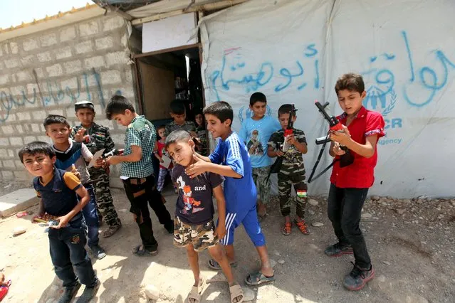 Displaced Iraqi boys, who fled from Islamic State violence in Mosul, play with their toy guns during Eid al-Fitr to mark the end of the fasting month of Ramadan at a refugee camp on the outskirts of Arbil July 17, 2015. (Photo by Azad Lashkari/Reuters)