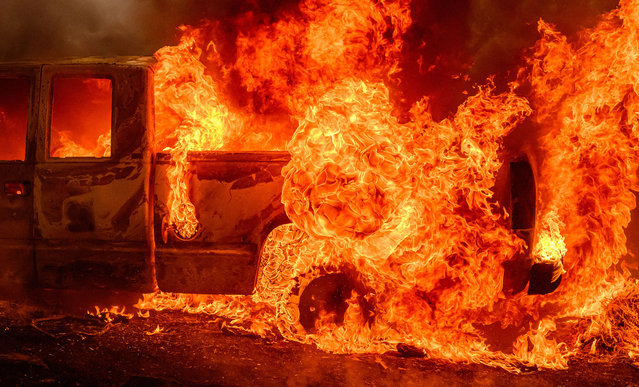 A vehicle burns as flames engulf a home nearby during the Thompson fire in Oroville, California on July 2, 2024. A heatwave is sending temperatures soaring resulting in red flag fire warnings throughout the state. (Photo by Josh Edelson/AFP Photo)