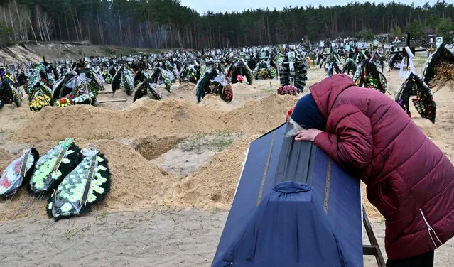 A woman reacts next to the coffin of her husband during a funeral at a cemetery in Irpin on April 19, 2022, where there are at least three rows of new graves for those killed during the Russian invasion of Ukraine. (Photo by Sergei Supinsky/AFP Photo)