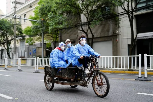 Workers in protective suits ride an electric tricycle during lockdown amid the coronavirus disease (COVID-19) pandemic, in Shanghai, China, April 15, 2022. (Photo by Aly Song/Reuters)