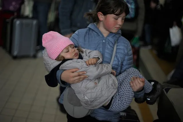Ukrainian refugees Tania, 2, and Galina, 11, wait in the ticket hall at Przemysl Glowny train station, after fleeing the Russian invasion of Ukraine, in Poland, April 4, 2022. (Photo by Kacper Pempel/Reuters)