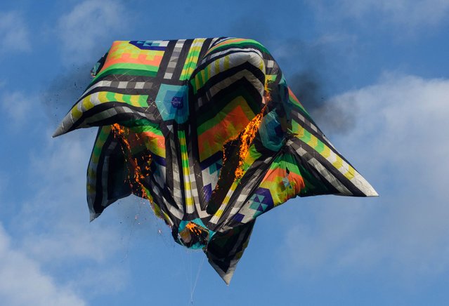 A hot air balloon flown by enthusiasts, without basket nor passengers, burns and falls to land during a tribute to mothers on Mother's Day, in Rio de Janeiro, Brazil, on May 14, 2023. (Photo by Tercio Teixeira/AFP Photo)