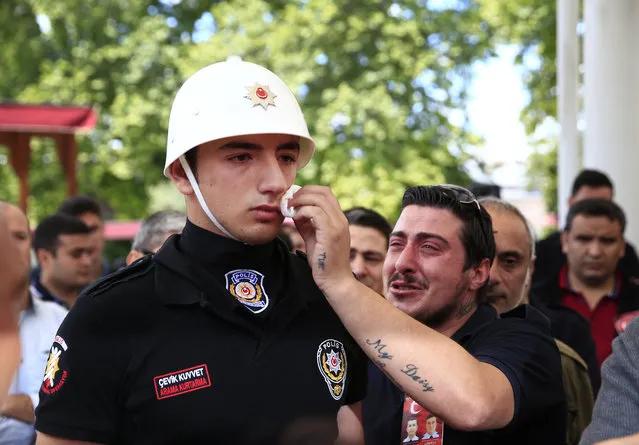 A relative, right, of one of the victims of Tuesday's explosion, wipes the face of a Turkish police officer, serving as a honor guard, during the funeral procession for two of the victims at Fatih mosque in Istanbul, Wednesday, June 8, 2016. The bomb attack, targeting a bus carrying riot police during rush hour traffic in Istanbul, has killed a number of people and wounded dozens of others. It marks the fourth bombing to hit the Turkish city this year and there was no immediate responsibility claim but Turkey has witnessed an increase in violence linked to Kurdish rebels and Islamic State militants. (Photo by Lefteris Pitarakis/AP Photo)