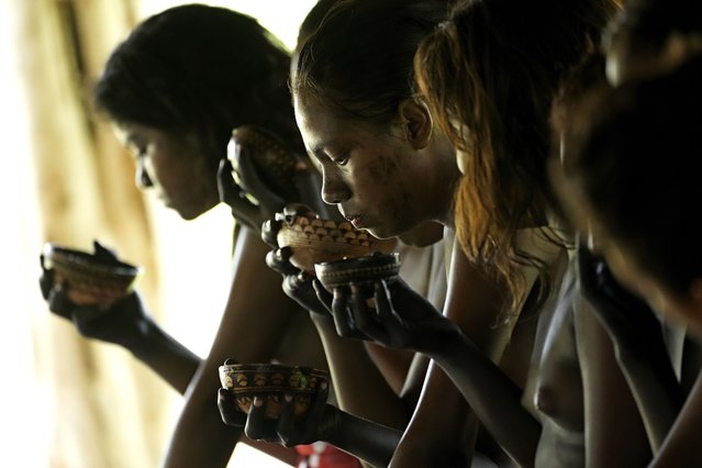 Girls drink a traditional porridge made from Cassava during the Wyra'whaw coming-of-age festival in the Ramada ritual center, in Tenetehar Wa Tembe village, located in the Alto Rio Guama Indigenous territory in Para state, Brazil, Saturday, June 10, 2023. Known as the Menina Moca in Portuguese, the three-day festival is for adolescent boys and girls in Brazil's Amazon. (Photo by Eraldo Peres/AP Photo)