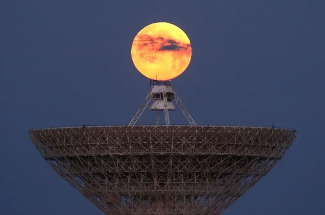 The moon is seen through clouds behind the radio telescope RT-70 in the village of Molochnoye, Crimea on May 16, 2022. (Photo by Alexey Pavlishak/Reuters)