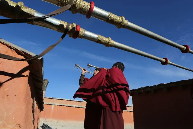 Monks play gyaling and dungchen, Tibetan ritual instruments, from a monastery rooftop at the end of a ceremony during the Tenchi Festival on May 24, 2014 in Lo Manthang, Nepal. The Tenchi Festival takes place annually in Lo Manthang, the capital of Upper Mustang and the former Tibetan Kingdom of Lo. Each spring, monks perform ceremonies, rites, and dances during the Tenchi Festival to dispel evils and demons from the former kingdom. (Photo by Taylor Weidman/Getty Images)