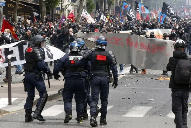Masked youths with labour union flags are seen during clashes with French gendarmes and riot police during a demonstration in Paris as part of nationwide protests against plans to reform French labour laws, France, June 14, 2016. (Photo by Jacky Naegelen/Reuters)