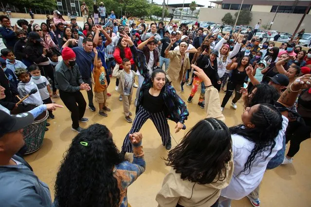 Central American migrants dance during an event named “Virtual Reality Baroque Opera” as they await the result of their asylum request to U.S, in Tijuana, Mexico on May 28, 2022. (Photo by Jorge Duenes/Reuters)