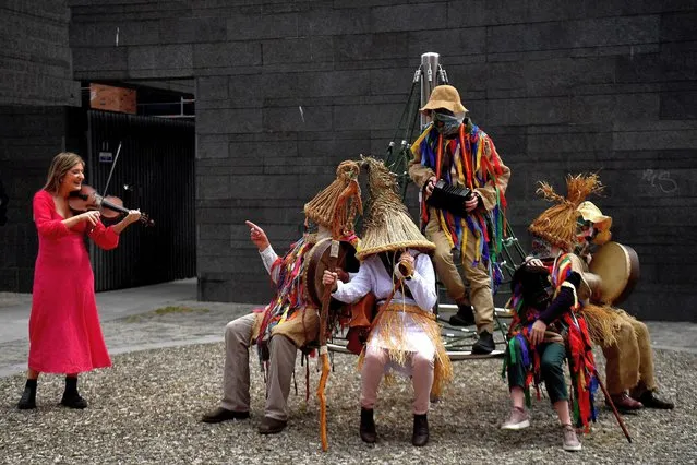 Doireann Glackin plays the fiddle next to a group of Mummers as they perform in Smithfield Square to highlight the upcoming Smithfield Fleadh traditional music and folk festival, in Dublin, Ireland, May 31, 2022. (Photo by Clodagh Kilcoyne/Reuters)