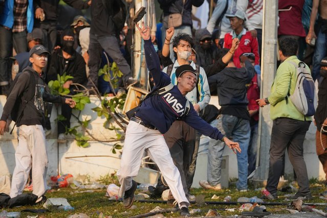 A student protester throws a rock toward riot police officers during a rally against controversial changes to election laws that could further enhance the political influence of outgoing President Joko Widodo, at the parliament building in Jakarta, Indonesia, Thursday, August 22, 2024. (Photo by Dita Alangkara/AP Photo)