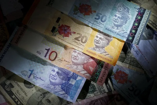 Malaysian ringgit notes of different denominations are seen on top of U.S. dollar notes in this file photo illustration taken in Singapore on March 14, 2013. The Malaysian ringgit hit a 16-year low on July 6, 2015 after reports linked the country's prime minister to probes into alleged corruption, while most emerging Asian currencies slid as Greeks rejected austerity measures for bailout money. (Photo by Edgar Su/Reuters)