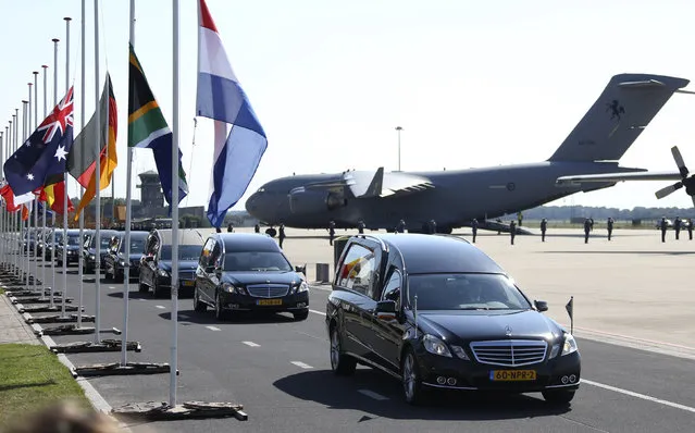 The convoy of hearses with the remains of the victims of Malaysia Airlines MH17 downed over rebel-held territory in eastern Ukraine, drives past international flags as it leaves Eindhoven airport to a military base in Hilversum July 23, 2014. (Photo by Francois Lenoir/Reuters)