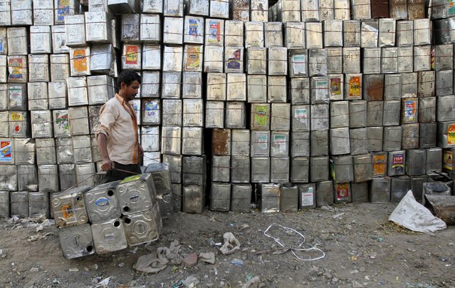 A man carries empty aluminium tins used for edible oil past a stack of tins at a recycling yard in the western Indian city of Ahmedabad, in this October 18, 2011 file photo. India plans to spend $1.5 billion in the next three years to help farmers grow oil palm trees in an area the size of New Jersey, government sources said, with Prime Minister Narendra Modi pushing to make the nation self-sufficient in edible oils this decade. (Photo by Amit Dave/Reuters)