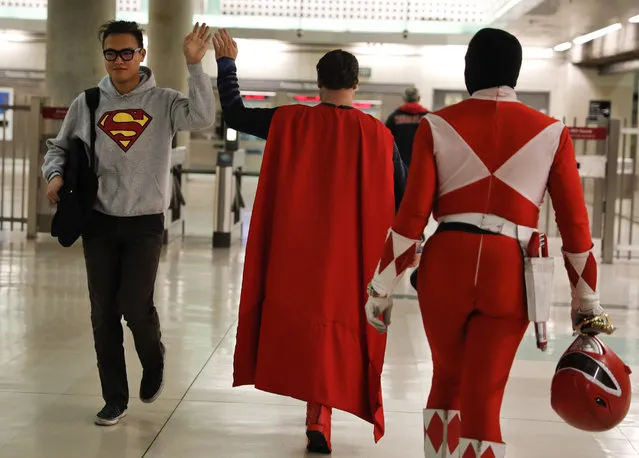 In this Tuesday, May 16, 2017 photo, Superman impersonator Justin Harrison, center, high-fives a commuter wearing a sweatshirt with a Superman symbol printed on it as he and his roommate, Reginald Jackson, in a Red Power Ranger costume, head back home after working on Hollywood Boulevard, in Los Angeles. “When I put on any costume of any character, I automatically feel like I am that character”. (Photo by Jae C. Hong/AP Photo)