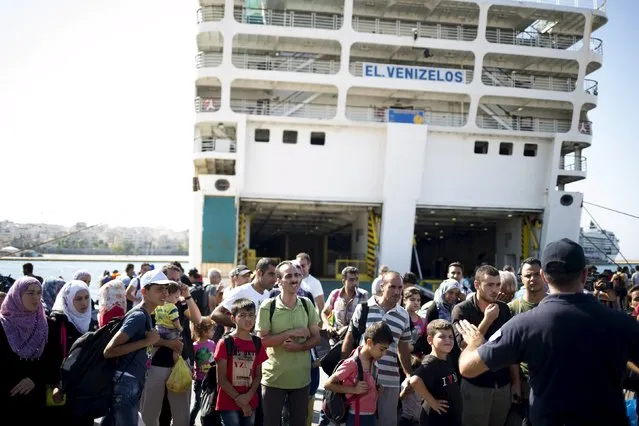Syrian refugees listen to a Greek policeman after arriving at the port of Piraeus near Athens onboard “Eleftherios Venizelos” passenger ship, Greece, August 20, 2015. (Photo by Stoyan Nenov/Reuters)