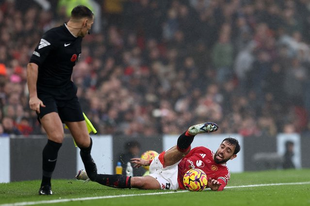 Manchester United's Portuguese midfielder #08 Bruno Fernandes falls next to the linesman during the English Premier League football match between Manchester United and Leicester City at Old Trafford in Manchester, north west England, on November 10, 2024. (Photo by Darren Staples/AFP Photo)