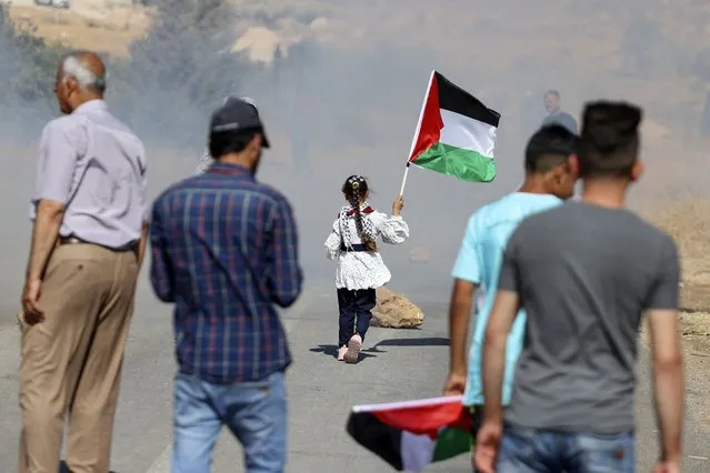 A Palestinian girl carries her country's national flag during demontrations against Israeli settler attacks near al-Mughayer village, east of Ramallah in the occupied West Bank, on July 12, 2022. (Photo by Abbas Momani/AFP Photo)