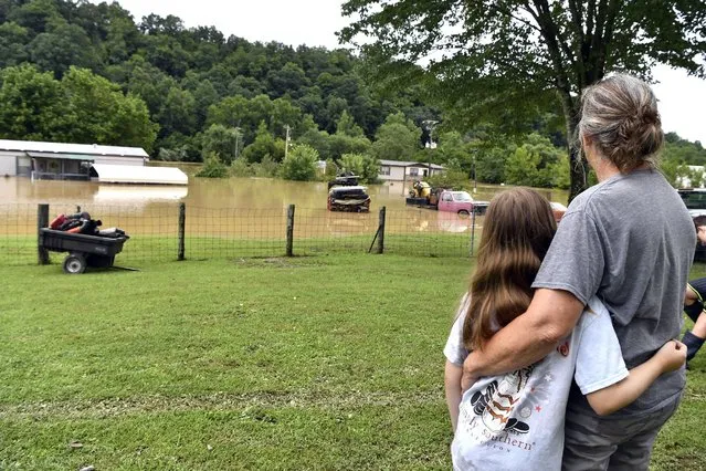 Bonnie Combs, right, hugs her 10-year-old granddaughter Adelynn Bowling watches as her property becomes covered by the North Fork of the Kentucky River in Jackson, Ky., Thursday, July 28, 2022. Flash flooding and mudslides were reported across the mountainous region of eastern Kentucky. (Photo by Timothy D. Easley/AP Photo)