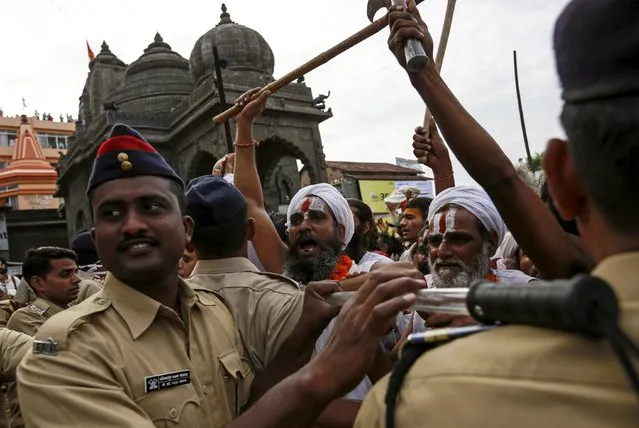 Sadhus or Hindu holy men are controlled by police as they arrive to take a dip in the Godavari river during the first Shahi Snan (grand bath) at Kumbh Mela, or Pitcher Festival in Nashik, India, August 29, 2015. (Photo by Danish Siddiqui/Reuters)