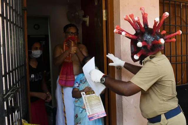 A policeman wearing a a coronavirus helmet distributes pamphlets to raise awareness about the COVID-19 coronavirus at a residential area during a government-imposed nationwide lockdown as a preventive measure against the COVID-19 coronavirus, in Chennai on April 12, 2020. (Photo by Arun Sankar/AFP Photo)