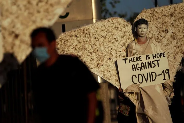 A religious activist from the evangelical church “Psalm 100”, dressed as an angel, stands with a sign outside a hospital caring for patients with coronavirus (COVID-19), in Ciudad Juarez, Mexico on April 18, 2020. (Photo by Jose Luis Gonzalez/Reuters)