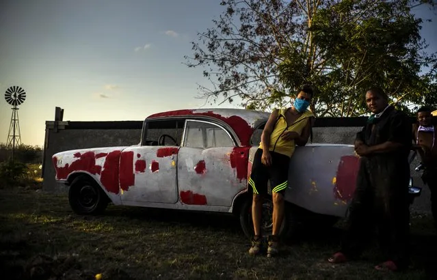 Workers who repaint classic American cars wear masks as a precaution against the spread of the new coronavirus, as they rest at sunset in Wajay, Havana, Cuba, Thursday, April 23, 2020. Cuban authorities are requiring the use of masks for anyone outside their homes. (Photo by Ramon Espinosa/AP Photo)