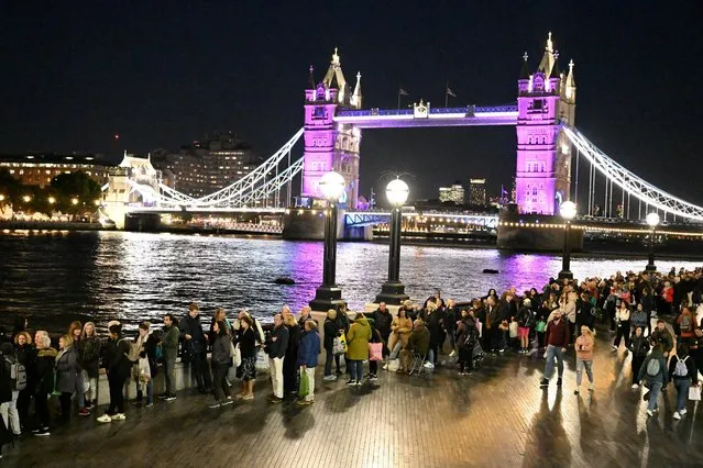 People wait in a queue to pay their respects as the Tower Bridge is lit up in purple to honour Britain's Queen Elizabeth, following her death, in London, Britain on September 16, 2022. (Photo by Clodagh Kilcoyne/Reuters)