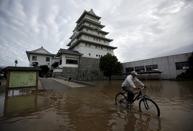 A local resident riding a bicycle goes through a residential area flooded by the Kinugawa river, caused by typhoon Etau, in front of the castle-shaped Joso City local interchange center known as Toyota Castle where hundreds of evacuees from an area flooded were stuck overnight, in Joso, Ibaraki prefecture, Japan, September 11, 2015. (Photo by Issei Kato/Reuters)