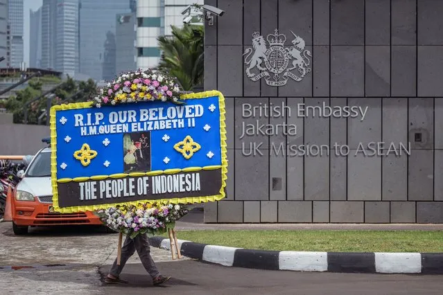 A man delivers a condolence wreath at the British embassy following the death of Queen Elizabeth II, in Jakarta on September 9, 2022. Queen Elizabeth II, the longest-serving monarch in British history and an icon instantly recognisable to billions of people around the world, died at her Scottish Highland retreat on September 8 at the age of 96. (Photo by Bay Ismoyo/AFP Photo)