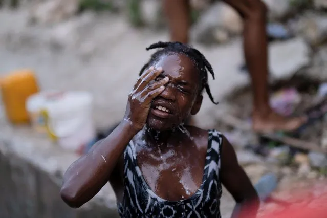 A girl bathes with fresh water collected from a well in Port-au-Prince, Haiti on October 12, 2022. (Photo by Ricardo Arduengo/Reuters)