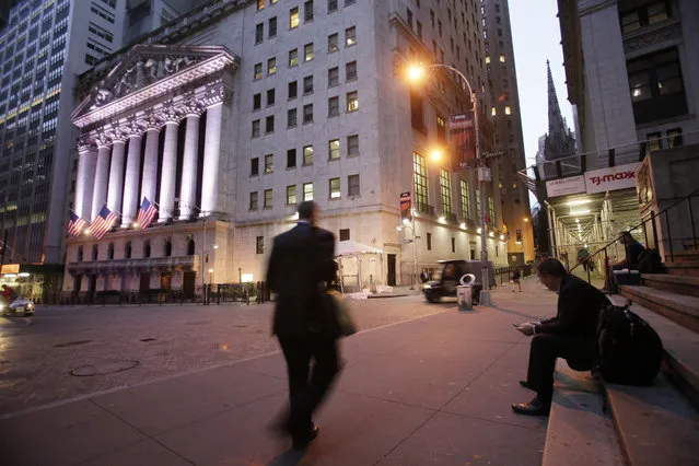 In this October 8, 2014, file photo, a man walks to work on Wall Street, near the New York Stock Exchange, in New York. Global stocks mostly fell on Monday, Nov. 6, 2017, and the price of oil hit a two-year high after a spate of high-profile arrests in Saudi Arabia unnerved some investors and suggested the kingdom could be more bullish in pursuing output cuts. (Photo by Mark Lennihan/AP Photo)