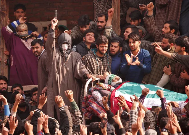 An unidentified man fires his pistol next to the body of Adil Rashid Chopan, a suspected militant, who according to the local media was killed in a gun battle with Indian security forces on Monday in Seer village, during his funeral procession at Lurrow village in Kashmir's Tral town November 21, 2017. (Photo by Danish Ismail/Reuters)
