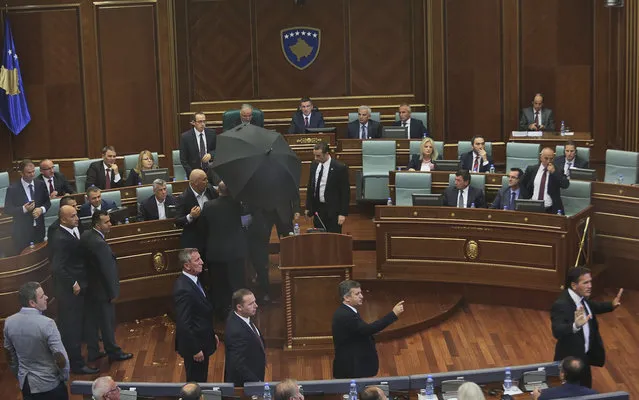 Bodyguards cover with umbrella Kosovo's Prime Minister Isa Mustafa escorting him away from the stand as opposition members throw eggs while he was addressing Kosovo's parliament in capital Pristina on Tuesday, September 22, 2015. Opposition lawmakers hurled eggs towards Kosovo's Prime Minister while he was addressing parliament on the latest agreement reached between Pristina and Belgrade in Brussels on August 25, 2015. (Photo by AP Photo)