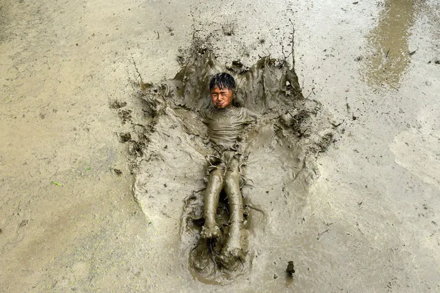 A boy plays in a rice paddy field during “National Paddy Day”, which marks the start of the annual rice planting season, in Tokha village on the outskirts of Kathmandu on June 29, 2020. Farmers in Nepal celebrate National Paddy Day as the annual rice planting season begins. (Photo by Prakash Mathema/AFP Photo)