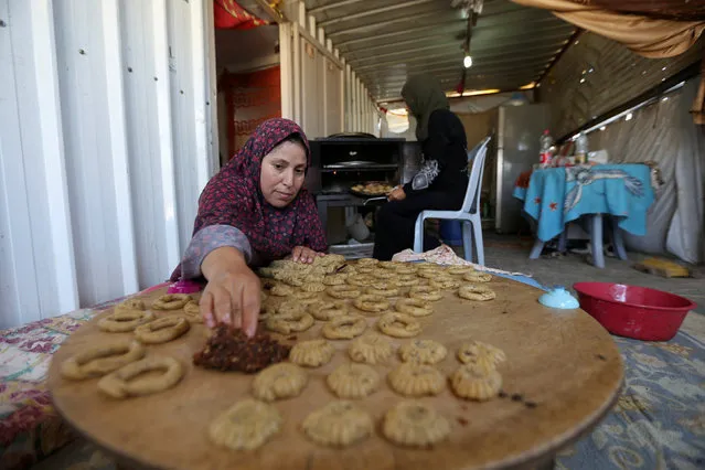 A Palestinian family, whose house was destroyed during 2014 war, make traditional cakes inside their makeshift shelter, ahead of Eid-al-Fitr celebrations in Khan Younis in the southern Gaza Strip July 3, 2016. (Photo by Ibraheem Abu Mustafa/Reuters)