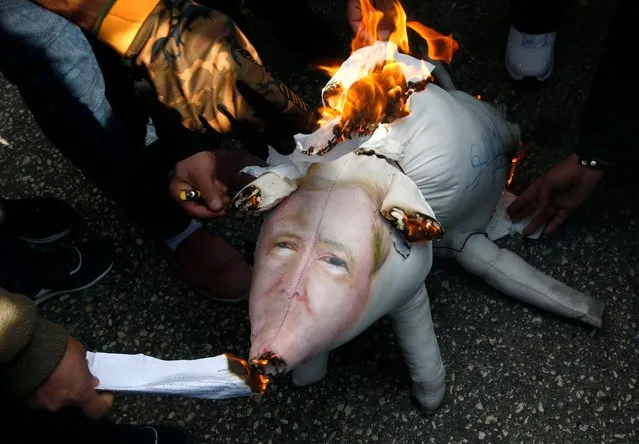 Palestinian protestors burn stuffed pillows in the shape of a pig and bearing an image of Israeli President Benjamin Netanyahu during a demonstration in the West Bank town of Hebron on December 13, 2017. (Photo by Hazem Bader/AFP Photo)