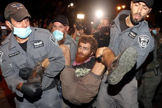 Police detain a man during a protest against Prime Minister Benjamin Netanyahu and his government's handling of the coronavirus crisis, near Netanyahu's residence in Jerusalem on July 23, 2020. Reimposed coronavirus curbs after a rise in new COVID-19 cases have prompted Israelis demanding better state aid to take to the streets in almost daily demonstrations. Public anger has also been fueled by corruption alleged against Netanyahu, who went on trial in May for bribery, fraud and breach of trust – charges he denies. (Photo by Ammar Awad/Reuters)